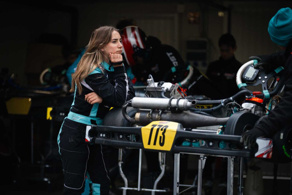 Emilia Urlaß aufgelehnt an einem aufgebockten Kart, während der Inspektion