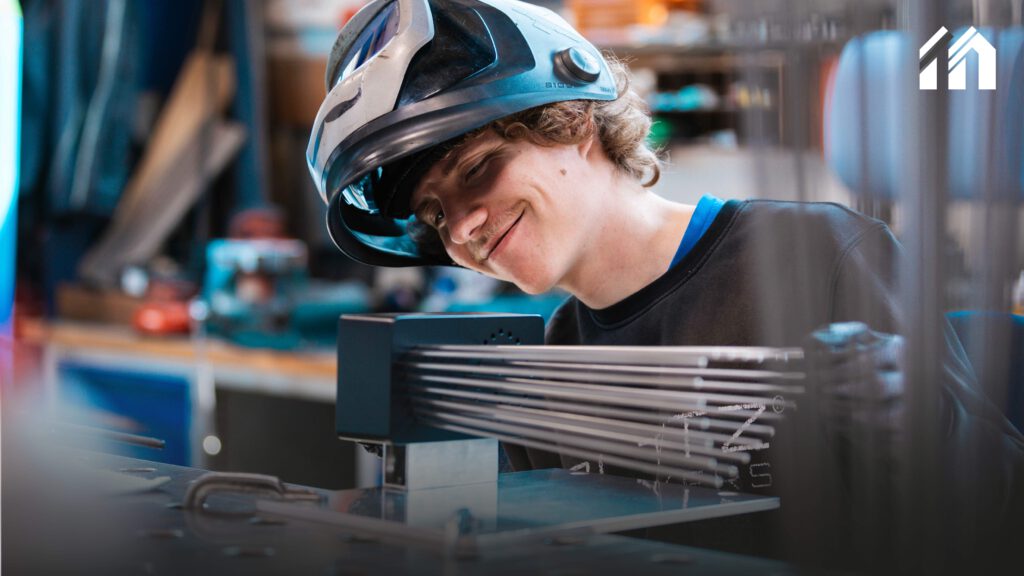 Metallbauer Merlin lächelnd während seiner Montage des MotoGP Pokals