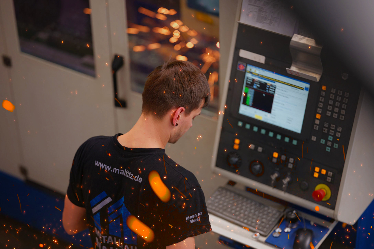 ein Mitarbeiter steht am Monitor der CNC Maschine