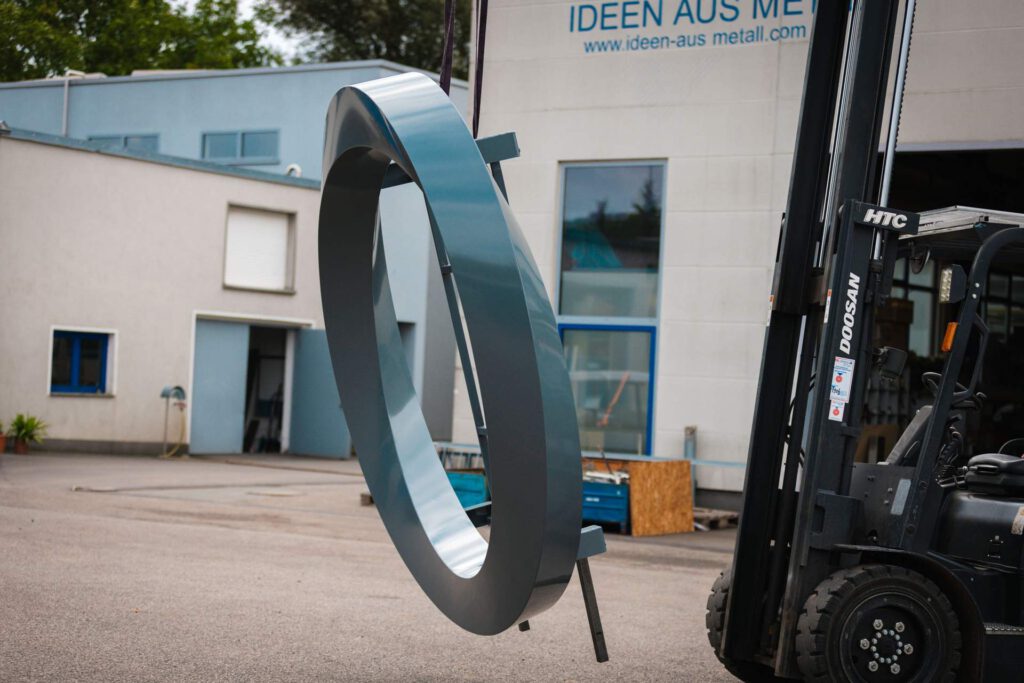 Das sich drehende Logo, hängend an einem Gabelstapler vor der Metallwerkhalle ei MALTITZ