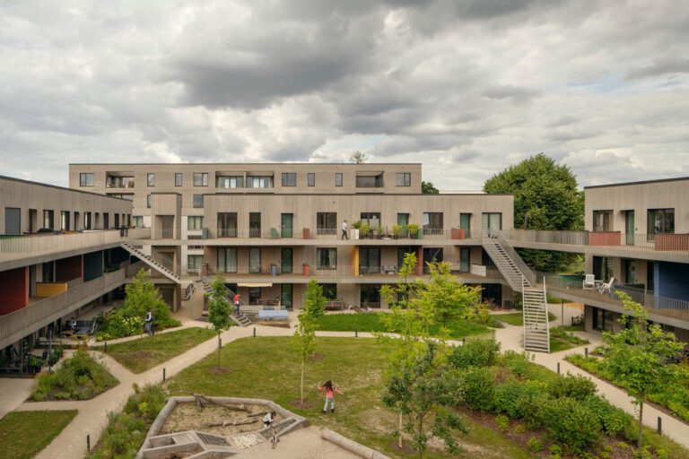 Modernes Holz-Hybrid-Wohnquartier Franklin Village in Mannheim mit markanten Stahltreppen und Edelstahlgeländern im begrünten Innenhof.