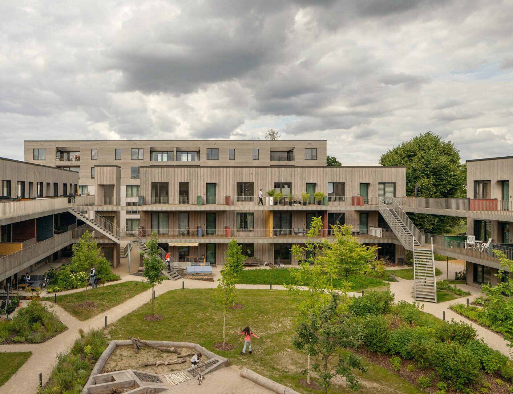 Modernes Holz-Hybrid-Wohnquartier Franklin Village in Mannheim mit markanten Stahltreppen und Edelstahlgeländern im begrünten Innenhof.