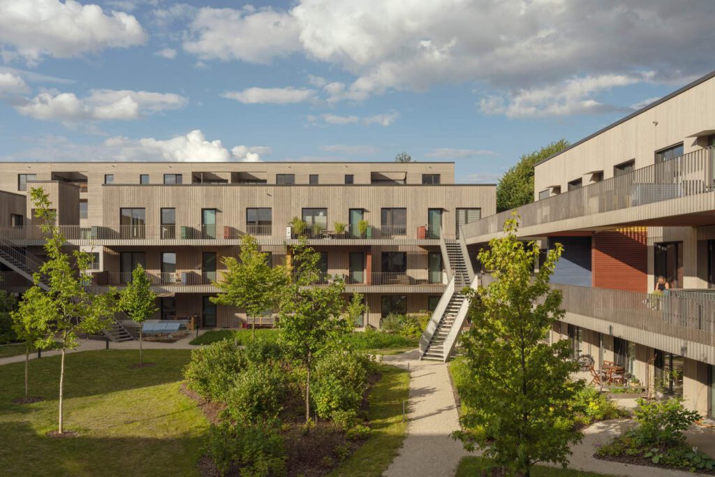 Blick in den begrünten Innenhof des Mehrgenerationenquartiers. Eine fertiggestellte Stahltreppe mit glasperlengestrahltem Edelstahlgeländer verbindet die verschiedenen Wohnebenen.