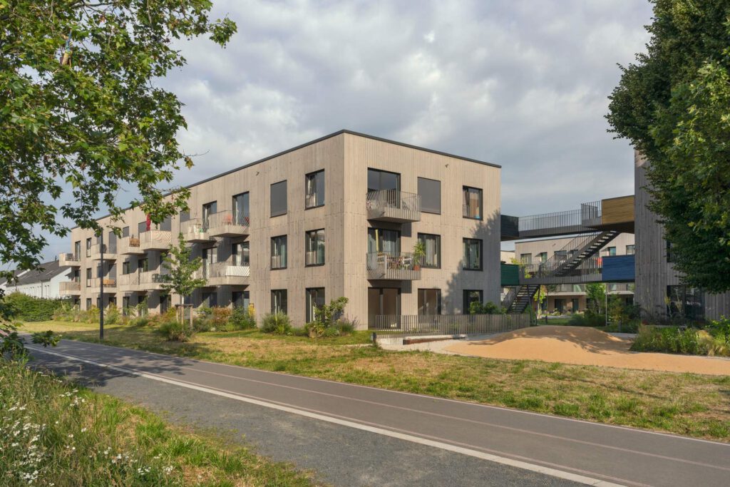 Außenansicht Eckgebäude: Die Außenansicht zeigt eines der fünf Neubaugebäude. Die Balkone sind mit umlaufenden Edelstahlgeländern ausgestattet, die Sicherheit und Ästhetik vereinen.