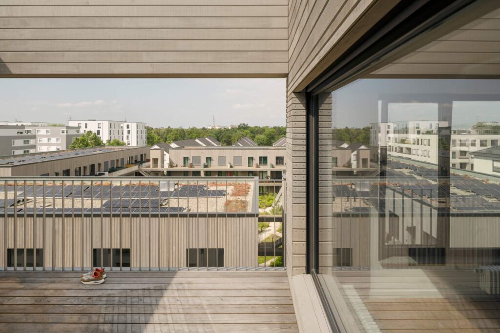 Nahaufnahme der Holzfassade mit Blick auf die installierten Edelstahl-Balkongeländer. Die glasperlengestrahlte Oberfläche sorgt für ein edles, mattes Finish.