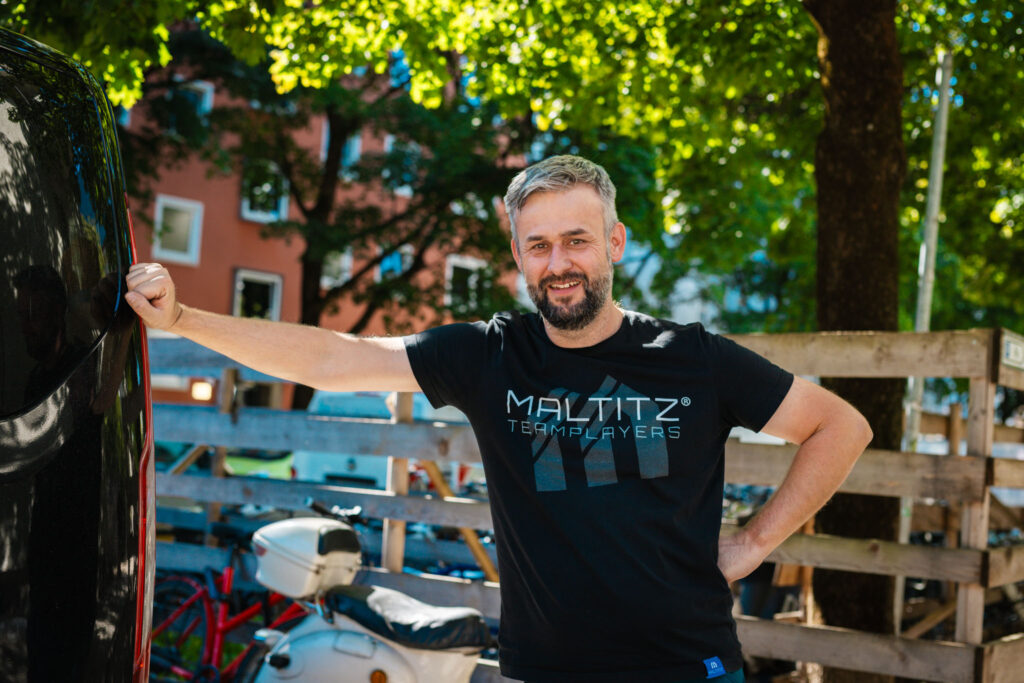 Mitarbeiter Alexander Fritzsch vor Baustelle des fertiggestellten Wohngebäudes in München nach Sanierung