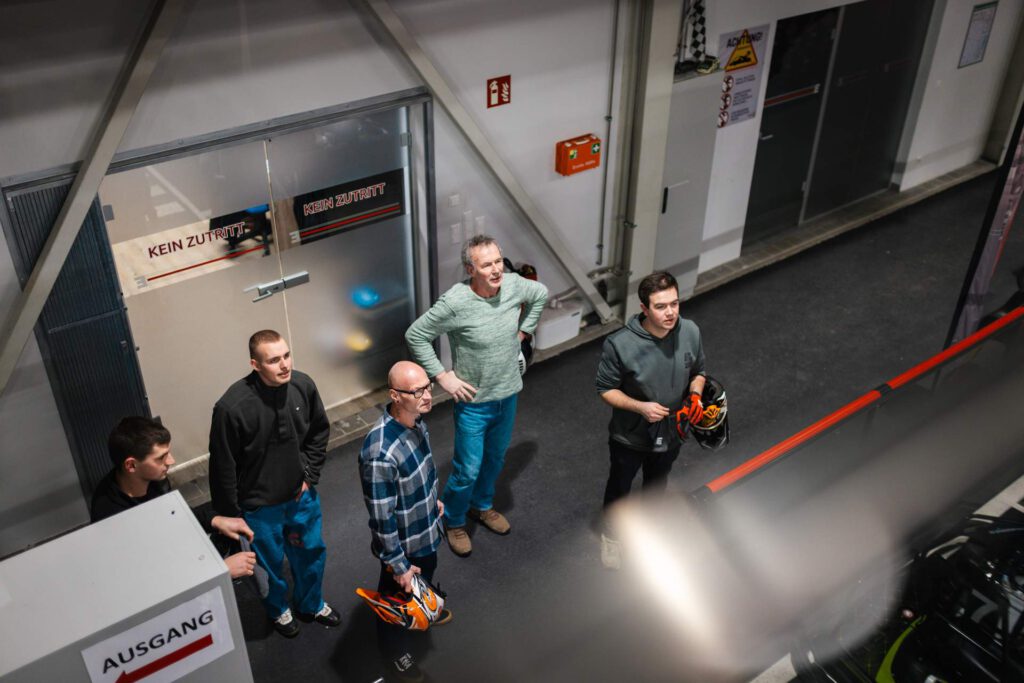 Vier Mitarbeiter von Maltitz Metallbau aus der Vogelperspektive fotografiert. Sie schauen gespannt auf das, was auf der Kartbahn vor sich geht.