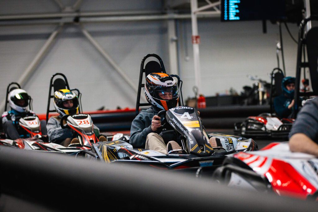  Konzentrierter Kartfahrer in schwarz-gelbem Kart wartet auf seinen Rundestart auf der Kartbahn.