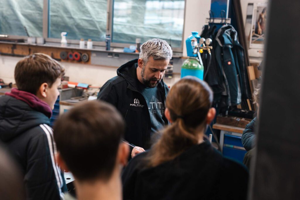 Alexander Fritzsch im Fachgespräch mit interessierten Schülern über die tägliche Arbeit und Werkzeuge in einem modernen Metallbaubetrieb.