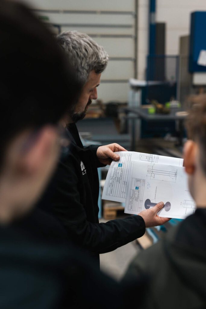 Detailansicht der Nachwuchsförderung: Alexander Fritzsch erläutert Schülern die Details einer technischen Zeichnung für die Fertigung.