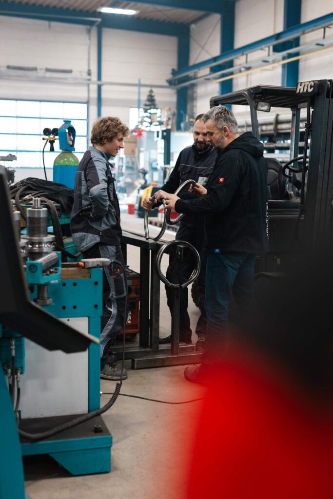 Alexander Fritzsch führt eine Gruppe durch die Werkstatt und unterhält sich mit 2 Mitarbeitern.