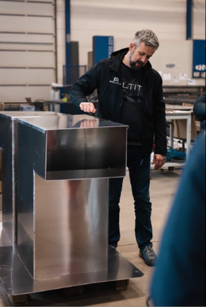 Alexander Fritzsch präsentiert ein fertiggestelltes Werkstück aus Edelstahl bei der Firma Maltitz während der Aktion „Schau rein! – Woche der offenen Unternehmen“, um die Präzision im Metallbau zu verdeutlichen.