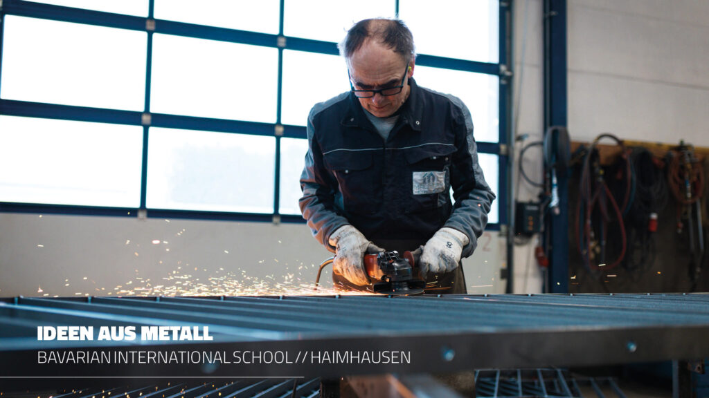 Ein Metallbauer von Maltitz bei der Arbeit in der Werkstatt: Mit einem Winkelschleifer bearbeitet er unter Funkenflug ein Sicherheitsgeländer für die Bavarian International School (BIS) in Haimhausen.