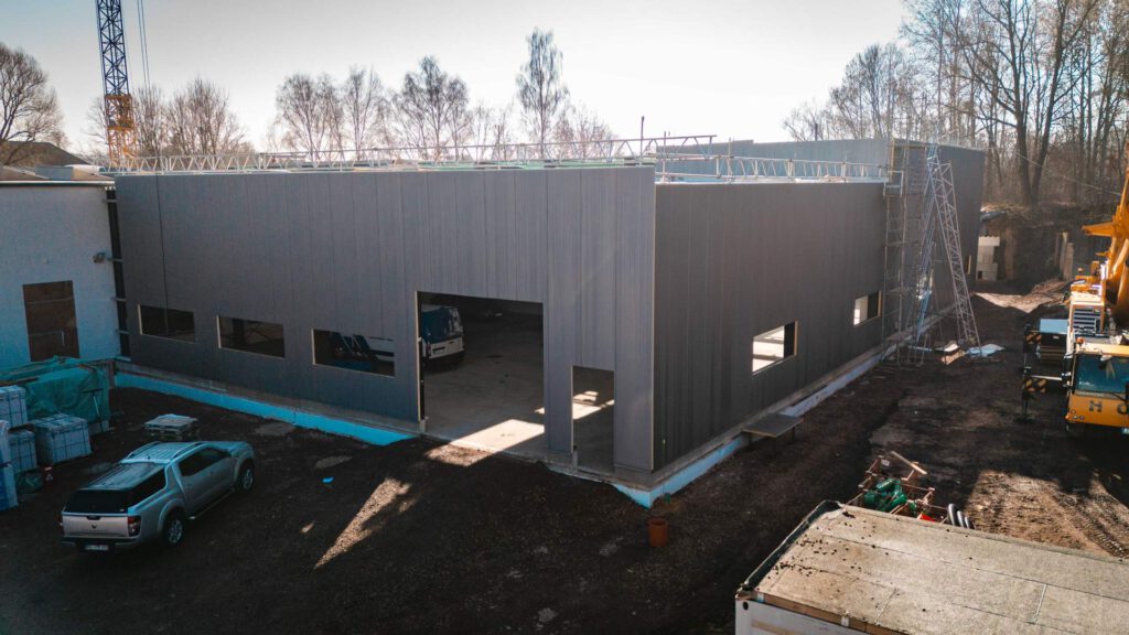 Außenansicht der modernen Fassadengestaltung der neuen Industriehalle von Metallbau Maltitz unter blauem Himmel.
