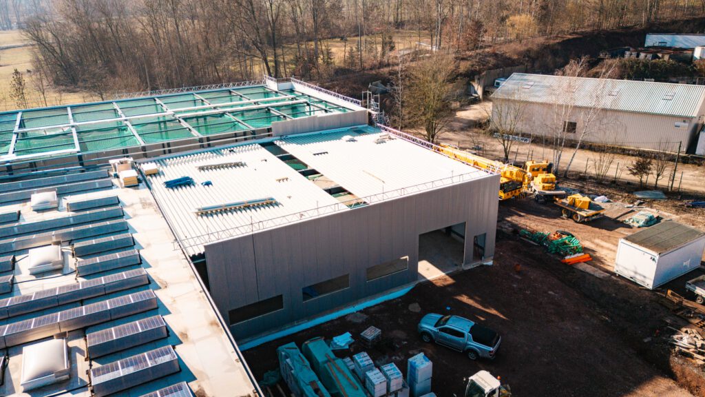 Luftbild der Dacharbeiten: Montage der Trapezbleche und Vorbereitung für die Photovoltaik-Anlage auf der neuen Halle.