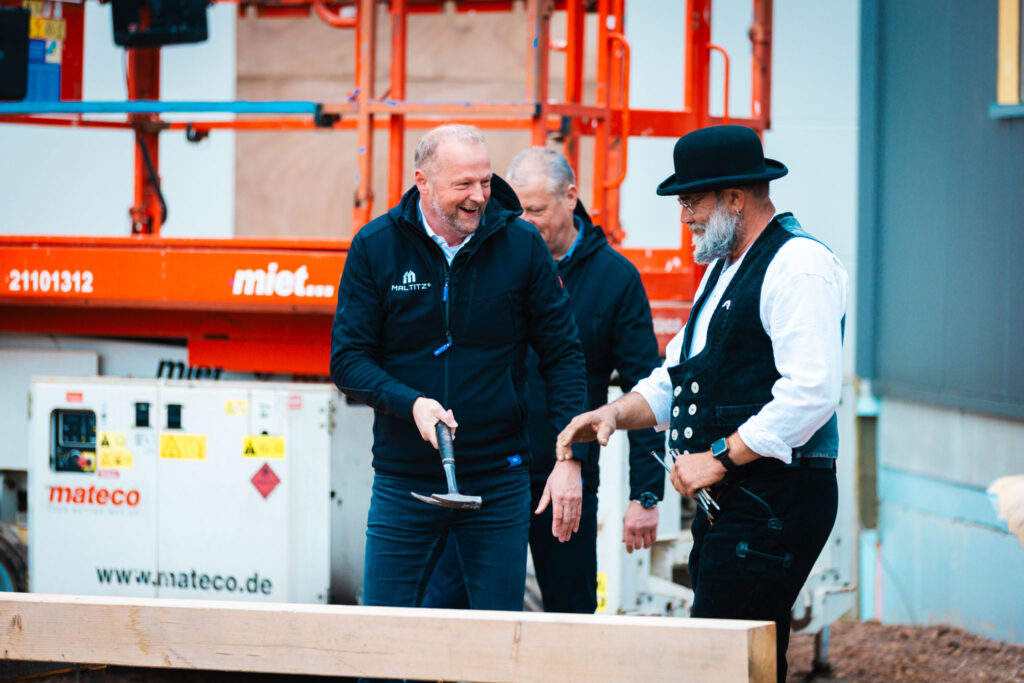Gute Laune und Tradition: Frank Maltitz und Zimmermann feiern das „Dach über dem Kopf“ bei Metallbau Maltitz.