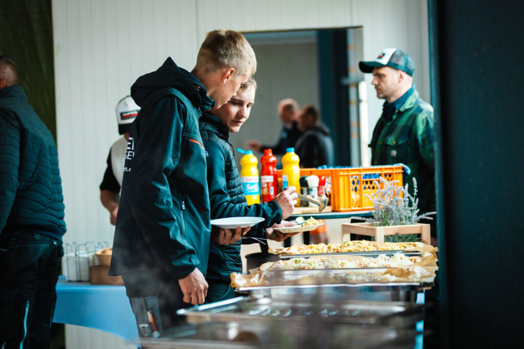 Mitarbeiter am Buffet beim Richtfest von Metallbau Maltitz bedienen sich an warmen Speisen in der neuen Halle.