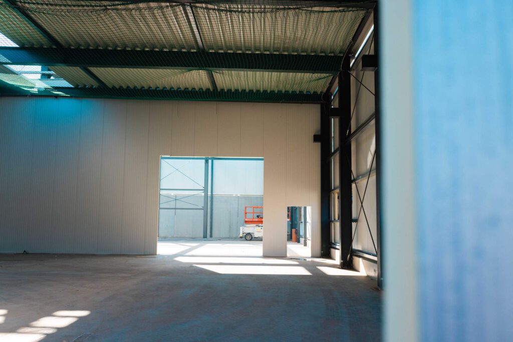 Helle Innenansicht der Rohbau-Halle mit Fokus auf die präzise Montage der Wandelemente.