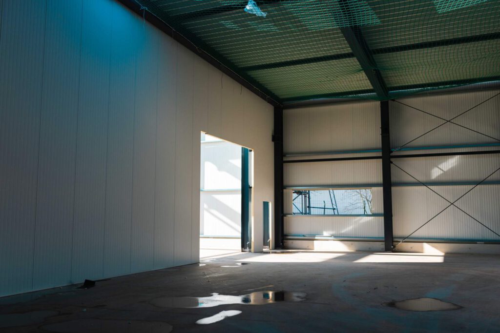 Blick aus der geschlossenen Halle afu die eigens gefertigten Stahlträgerelemente, daneben ist der Augang zu sehen