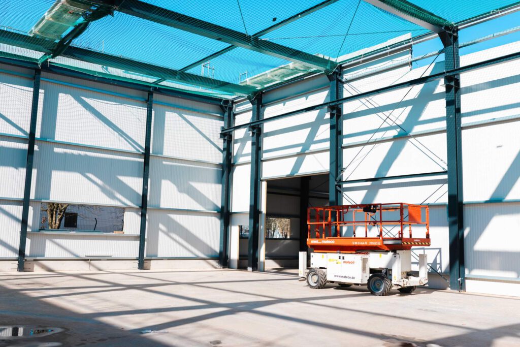 Einsatz moderner Technik: Eine Scherenbühne in der hohen Halle zur Montage der Dämmung und Fassade.