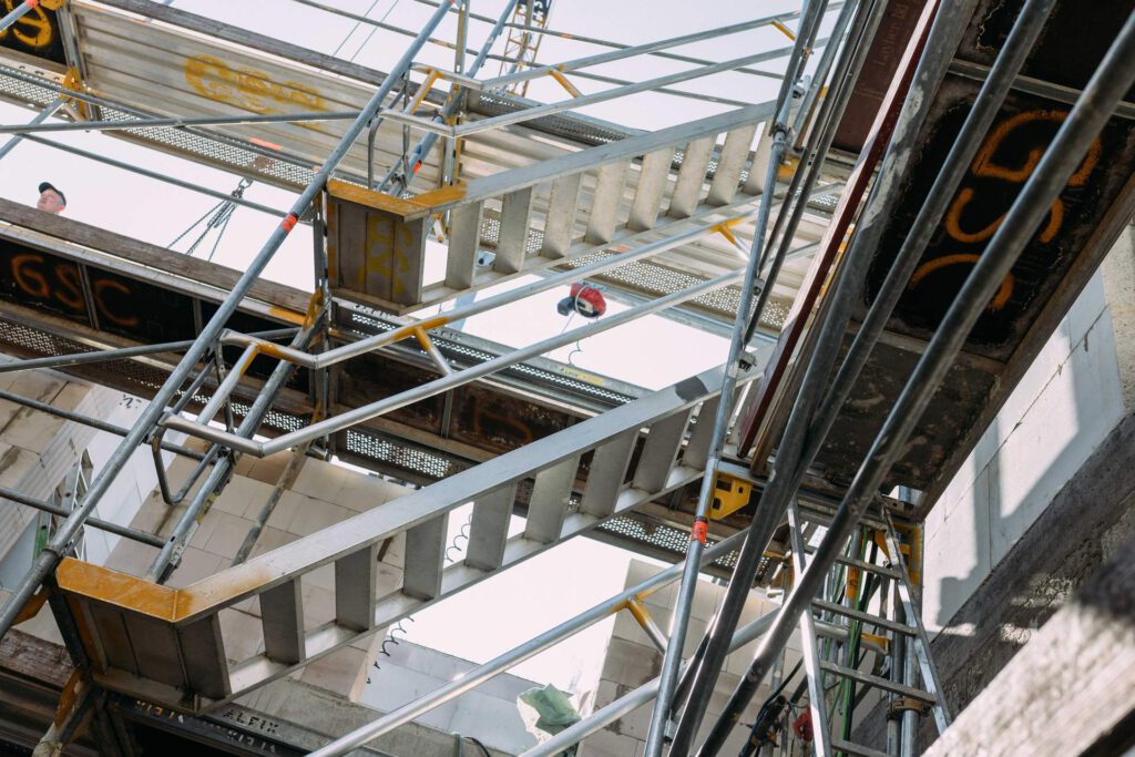 Blick durch das Baugerüst auf die massiven Betonwände und Filigrandecken des neuen Sozialbaus
