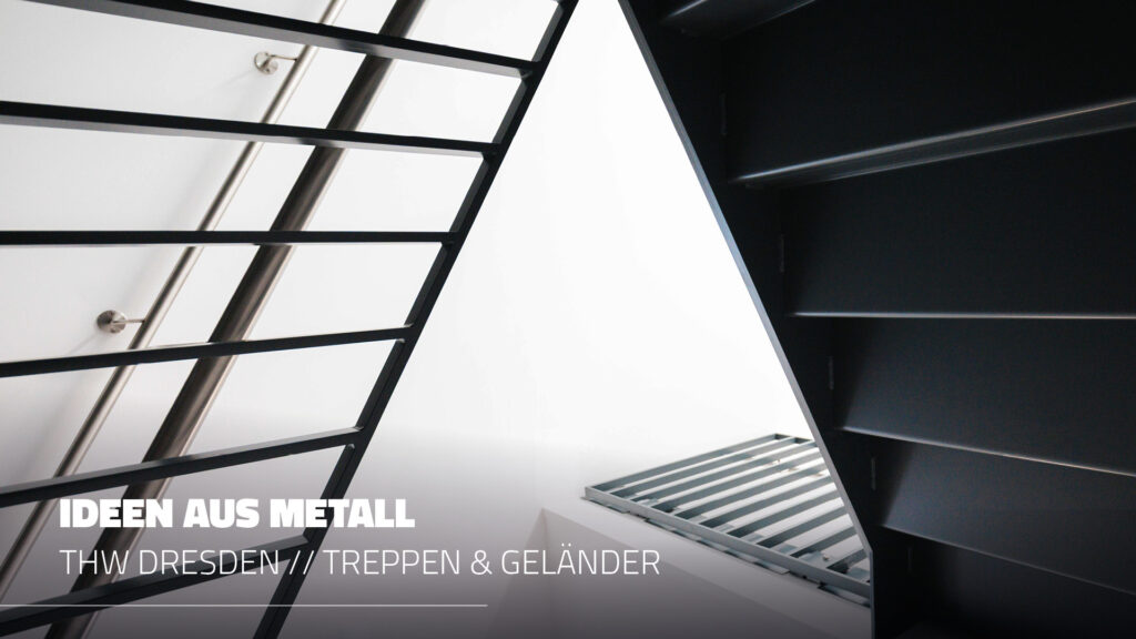 Modernes Treppenhaus-Design im THW Dresden: Blick von unten auf eine anthrazitfarbene Metalltreppe mit grafischen Geländerstreben und integriertem Edelstahl-Handlauf vor hellem Hintergrund.