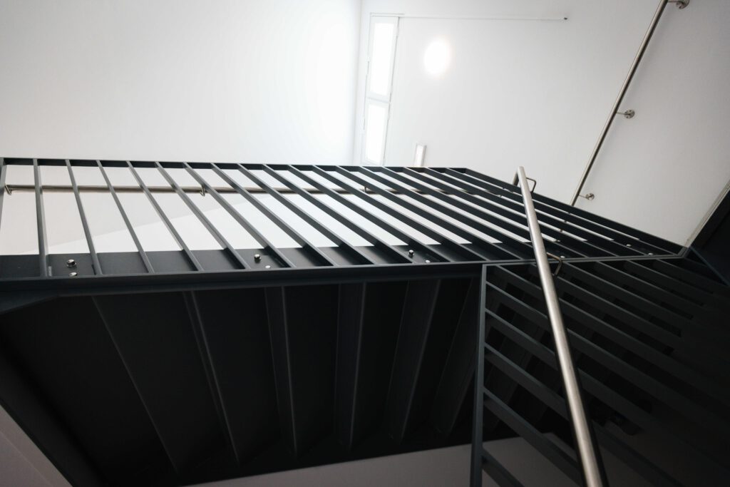 Untersicht einer massiven Stahltreppen-Konstruktion in Schwarz, die die architektonische Stabilität und das moderne Design der Metallbau-Arbeiten zeigt.