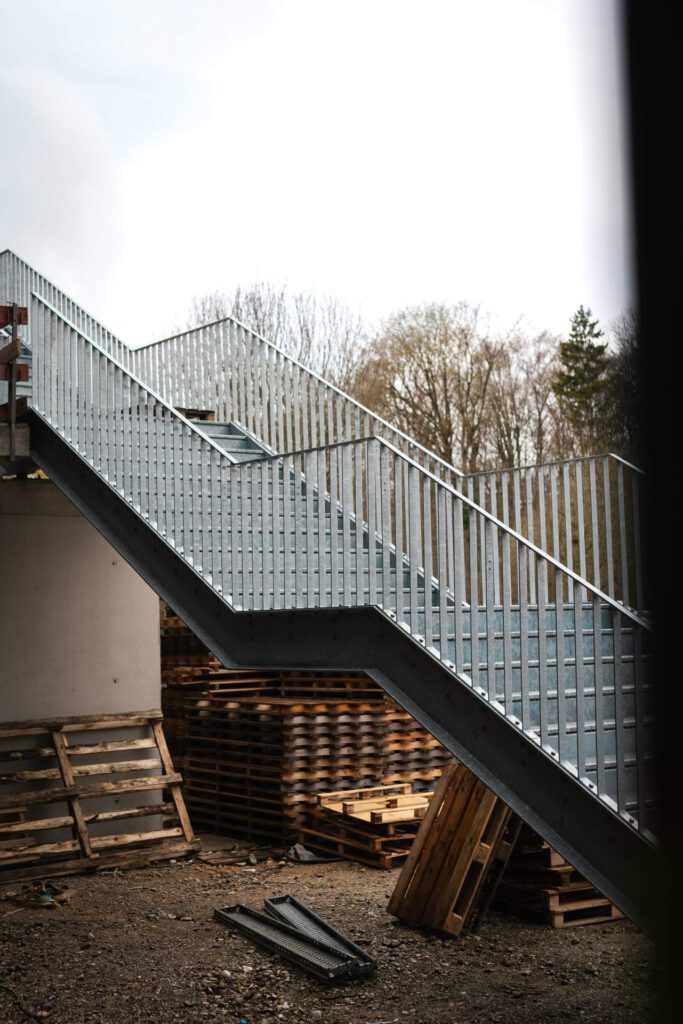Seitenansicht der wetterbeständigen, feuerverzinkten Stahltreppe als Fluchtweg vor einem modernen Schulgebäude.