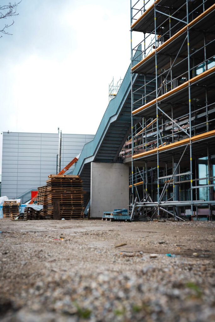 Perspektive von unten entlang der Fassade mit Blick auf die montierten Fluchttreppen und die umfassende Gerüstkonstruktion.