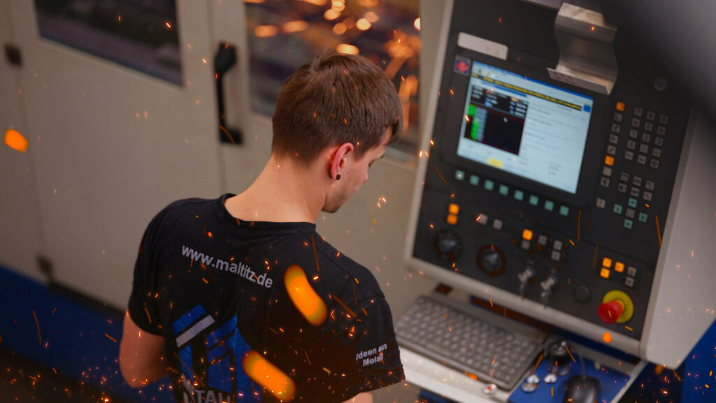 ein Mitarbeiter steht am Monitor der CNC Maschine