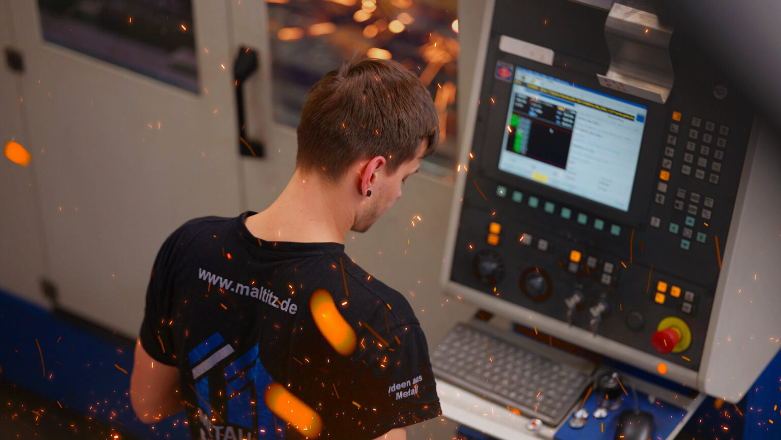 ein Mitarbeiter steht am Monitor der CNC Maschine