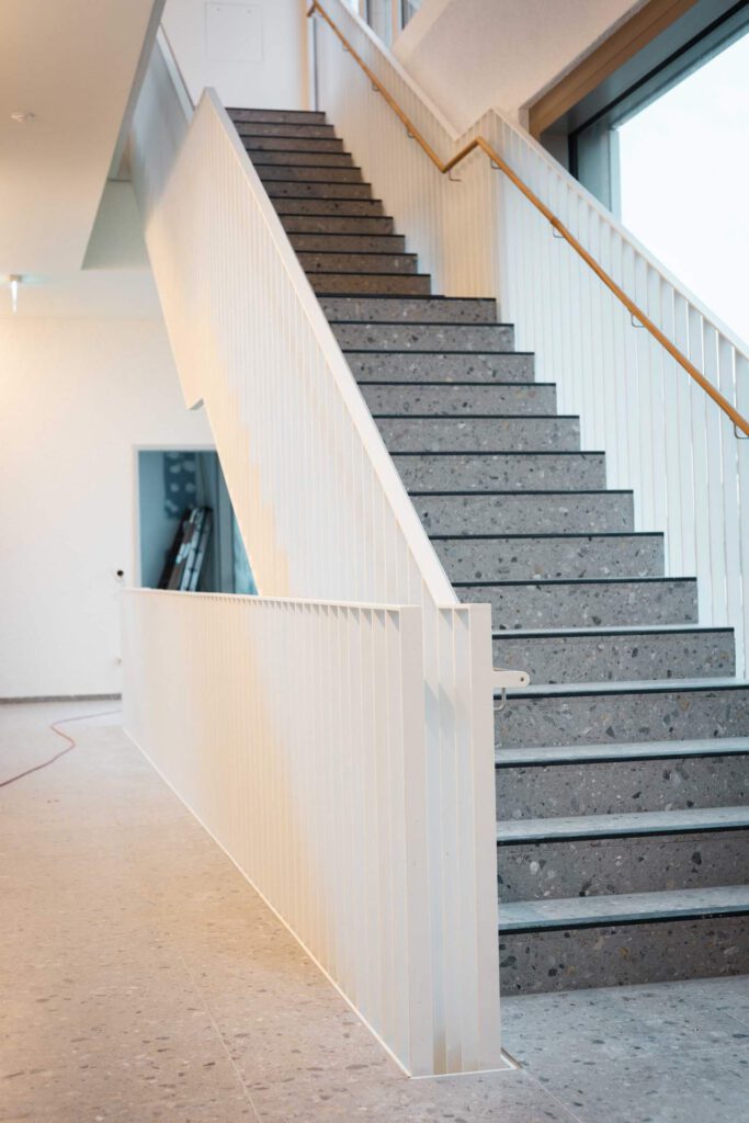 Moderne Treppenanlage mit weißem Metallgeländer und Edelstahl-Handlauf als individuelle Metallbau-Lösung in München