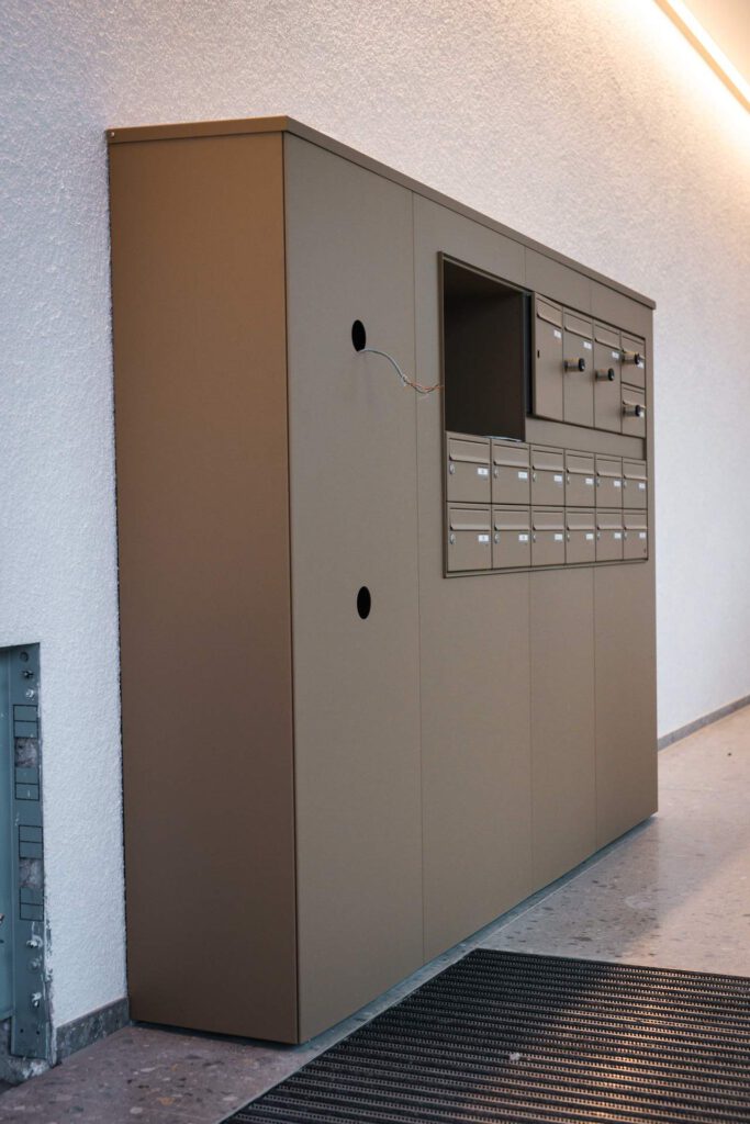 Individuell gefertigte Briefkastenanlage aus Metall mit nahtloser Integration in die Wandverkleidung der Meiller Gärten