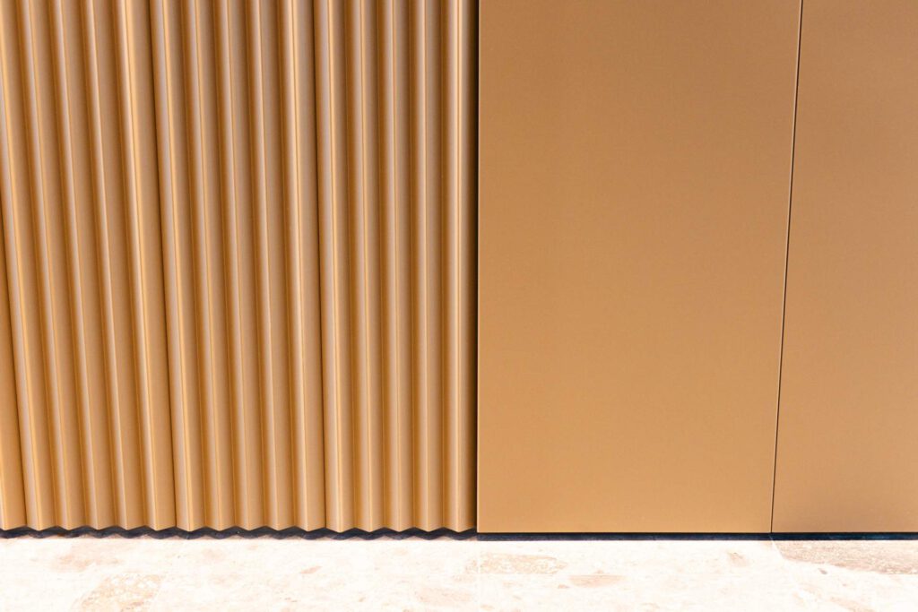 Detailansicht der aufwendig gefalteten Metallfassade mit glatten Verkleidungselementen im Foyer der Meiller Gärten
