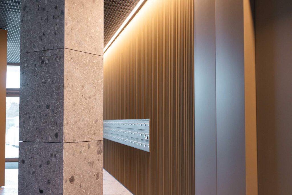 Gefaltete Metallfassade mit nahtlos integrierter Briefkastenanlage im Foyer der Meiller Gärten in München