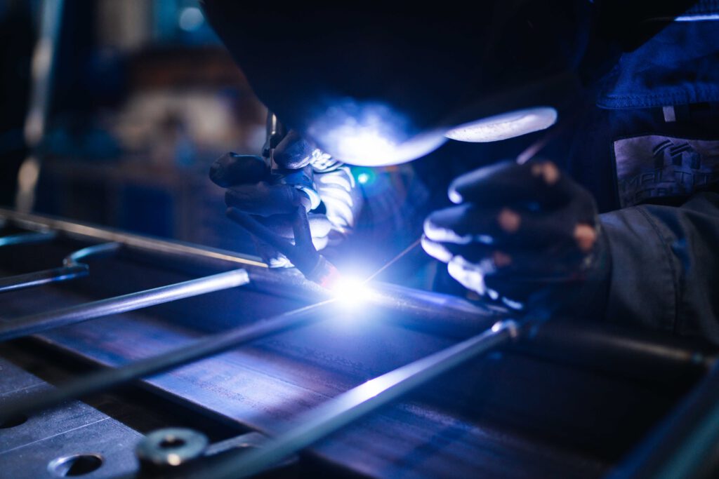 Metallarbeiter bzw. Schweißer führt präzise WIG-Schweißarbeiten an Metallrohren in einem Industriebetrieb aus.