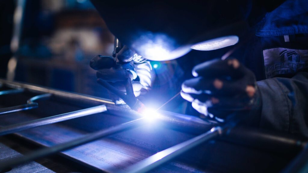 Metallarbeiter bzw. Schweißer führt präzise WIG-Schweißarbeiten an Metallrohren in einem Industriebetrieb aus.